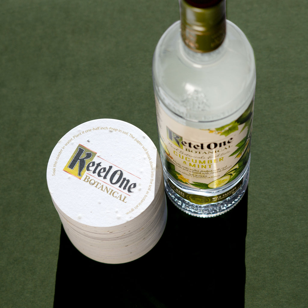 Stack of plantable coasters next to bottle of vodka